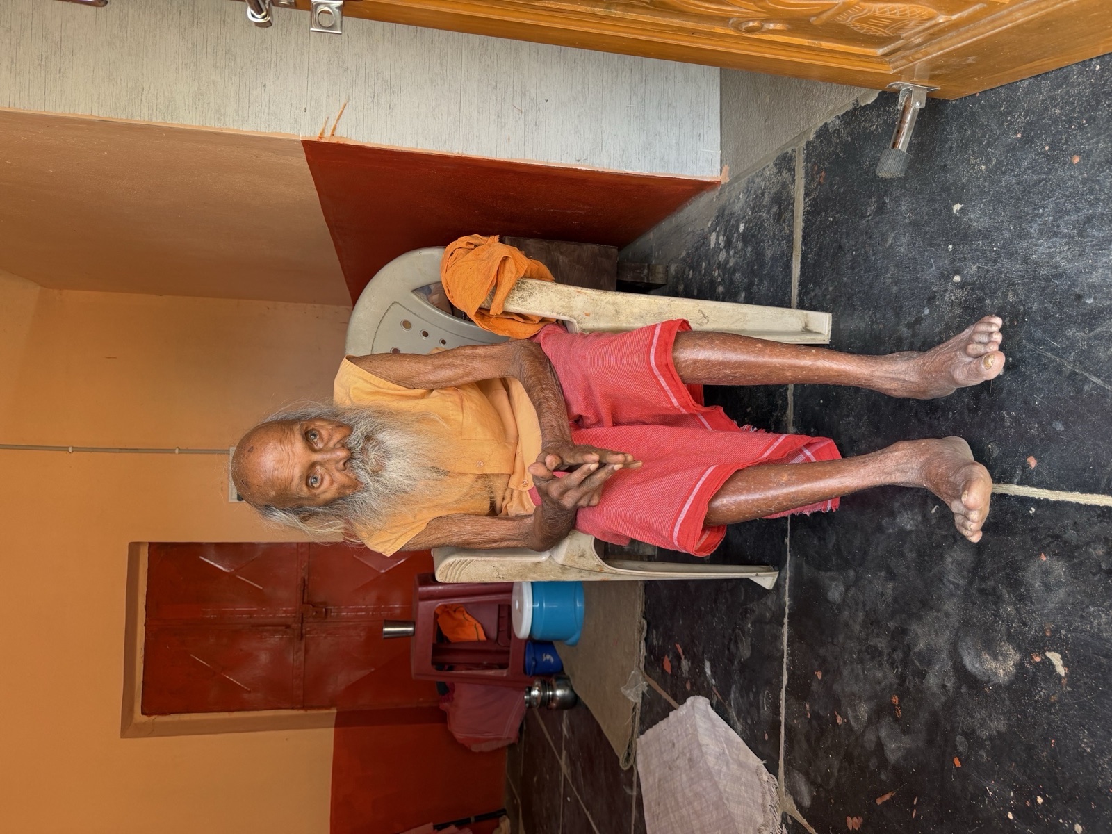 The elderly Swamiji seated beside the Rishimukha cave complex